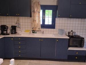a kitchen with blue cabinets and a microwave at arome de grenade in Nea Epidavros