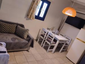 a living room with a couch and a table with chairs at arome de grenade in Nea Epidavros