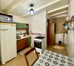 a kitchen with a refrigerator and a table and a stove at Casa do Aconchego - Quitinete I in Governador Celso Ramos