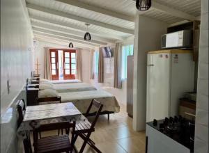 a room with four beds and a kitchen with a refrigerator at Casa do Aconchego - Quitinete I in Governador Celso Ramos