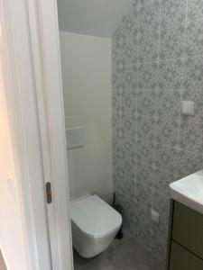 a bathroom with a toilet and a tiled wall at The Ocean View Luz in Luz