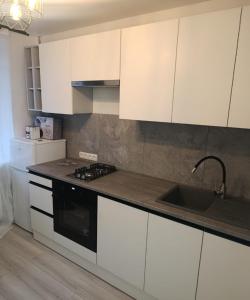 a kitchen with white cabinets and a sink and a stove at Loft Like View in Izmail