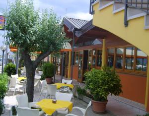 un ristorante con tavoli gialli, sedie bianche e un albero di Albergo Primavera a Senigallia