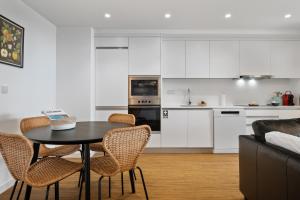 a kitchen with white cabinets and a table and chairs at Oceanfront Bliss - Atlantico residences in Câmara de Lobos