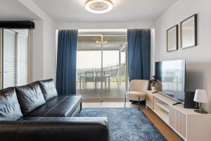 a living room with a black leather couch and a television at Oceanfront Bliss - Atlantico residences in Câmara de Lobos