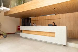 a woman sitting at a reception desk in a lobby at Sereno Hotel in Cabo Frio