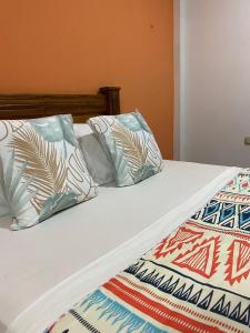 a bed with four pillows on it at Coccoloba Beach Hotel in Dibulla