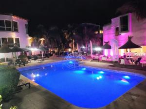 a swimming pool with blue water at night at Hotel El Cid in Villa Carlos Paz