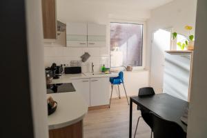 a small kitchen with white cabinets and a blue chair at Interior Apartments - Service Apartments in Bahnhofsnähe und UNESCO-Bergpark mit Parkplatzmöglichkeit, EBK, kinderfreundlich, Familienzimmer in Kassel