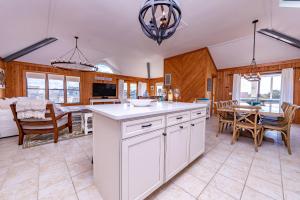a kitchen with white cabinets and a dining room with a table at Duck Diamond - Sanderling, Ocean View, 95 Yds to Beach, Hot Tub, Sauna, Community Pool in Duck