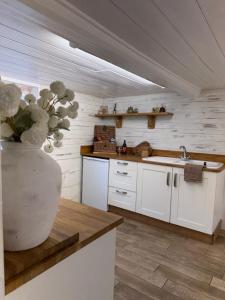 a kitchen with white cabinets and a vase of flowers at Beehive Cottage in Beccles