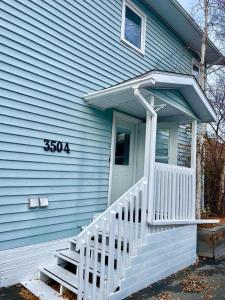 a blue house with a white porch and stairs at Aurora views from 2 br apartment by lake in Yellowknife