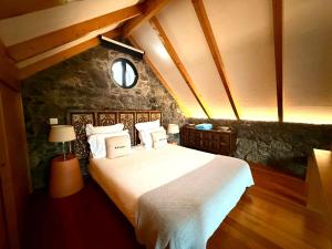 a bedroom with a large white bed with a stone wall at Palheiros do Serrado by Real Vision in Estreito da Calheta