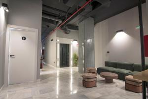 a lobby with a green couch and some stools at Hostel Superlativo Trinidad in Málaga