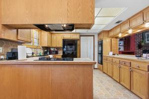 a large kitchen with wooden cabinets and a sink at Rustic Retreat 5-BR Home with Backyard Oasis in Baton Rouge