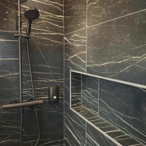 a bathroom with a shower with a black marble wall at Riverside Toulouse (Savory) in Blagnac