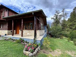 a log house with flowers in front of it at Luminosa Patagónia in Lago Puelo