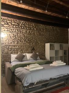 a bedroom with a large bed with a stone wall at Teatro Vecchio 11 in Bassano del Grappa