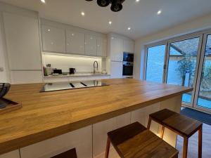 a kitchen with a large wooden counter with stools at Harbour Retreat Cottage 3 bedroom in Poole