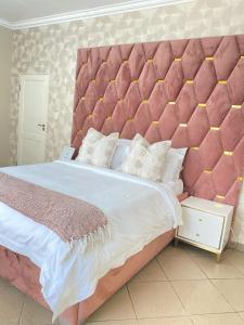 a large bed with a large pink padded headboard at Andisa Airport Escape in Kempton Park +51 photos