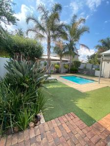 a backyard with a swimming pool and palm trees at Andisa Airport Escape in Kempton Park