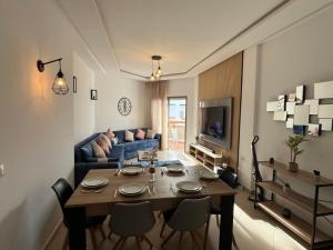 a living room with a table and a blue couch at Beachfront Apartment in Assilah, Private Solarium, 4 Pools, Secure Residence, WiFi, Parking in Asilah