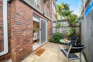 a patio with a table and chairs on a brick wall at Sunshine Hideaway - Easy Beachside Living in Mooloolaba