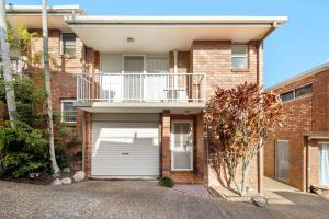 a brick house with a garage and a balcony at Sunshine Hideaway - Easy Beachside Living in Mooloolaba