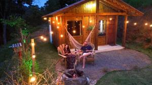 two people sitting in a hammock in front of a cabin at Cabana Pouso Sereno in Domingos Martins +5 photos