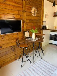 a kitchen with a table with chairs and a tv at Cabana Pouso Sereno in Domingos Martins