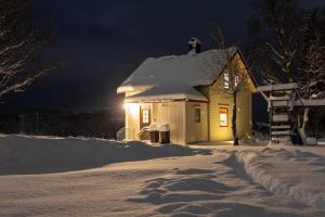 a small house in the snow at night at Old farm house & sauna in Stunes