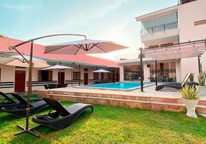 a house with a swimming pool with chairs and an umbrella at Hotel La Villa Mollendo in Mollendo
