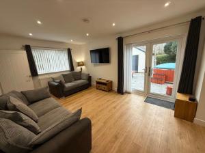a living room with a couch and a sliding glass door at The Farmhouse at Moss Bank Farm in Wrexham