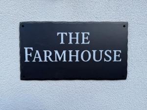 a sign that says the farm house on a wall at The Farmhouse at Moss Bank Farm in Wrexham