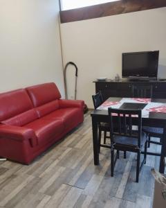 a living room with a red couch and a table at les lauriers in Saint-Sernin