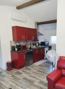 a kitchen with red cabinets and a red couch at les lauriers in Saint-Sernin