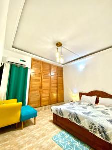 a bedroom with a bed and a yellow chair at Appartement moderne 2 chambres Grand-Bassam, Pharmacie Yélé in Moosou