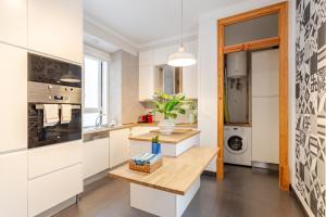 a kitchen with white cabinets and a wooden table at Cais Sodré Spacious Apartment in Lisbon