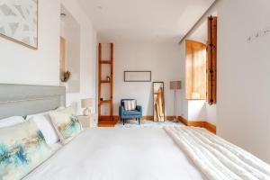 a bedroom with a white bed and a blue chair at Cais Sodré Spacious Apartment in Lisbon