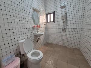 a white tiled bathroom with a toilet and a sink at Appartement moderne 2 chambres Grand-Bassam, Pharmacie Yélé in Moosou +9 photos