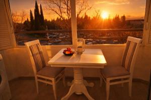 a table with a bowl of fruit and a window with the sunset at Luxury Apartment-Aurora 33 Free Parking City Center in Podgorica
