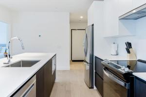 a kitchen with white counters and a stainless steel refrigerator at Alpine Living - Modern 2 Bedroom Condo in Revelstoke
