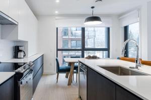 a kitchen with white counters and a sink and a table at Alpine Living - Modern 2 Bedroom Condo in Revelstoke