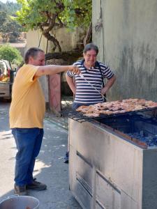 a man and a woman cooking meat on a grill at Casa Penafalcão in Castelo Branco