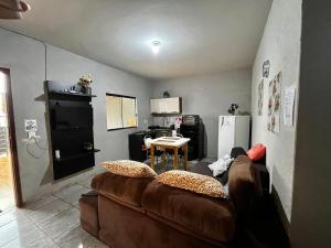 a living room with a brown couch and a kitchen at Loft B - individual Mobiliado com Ar-condicionado in Dourados