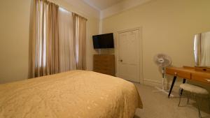a bedroom with a bed and a desk and a television at Squatters Cottage in Port Augusta