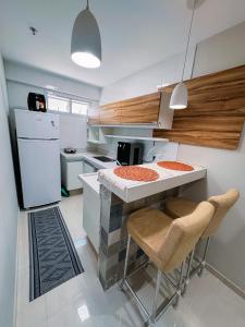 a kitchen with a counter and two chairs in it at FLAT MANDAI Praia do Forte - Cabo Frio - RJ in Cabo Frio