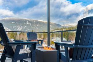 two chairs and a fire pit on a balcony with mountains at The View - Luxury Penthouse Condo in Revelstoke