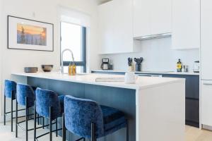 a kitchen with a white counter and blue chairs at The View - Luxury Penthouse Condo in Revelstoke +23 photos