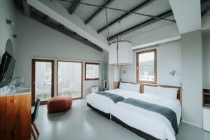 a bedroom with a large white bed and windows at KOTOBUKI Hotel in Kanoya